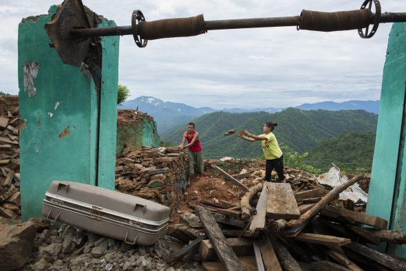Nepal, Gorkha District, Ramele, Gorkha. Family cleaning up their house damaged by the earthquake.