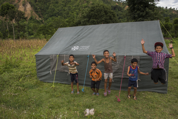 Nepal, Gorkha District, Arughat, Gorkha. Nepal Youth Foundation. Destruction after the earthquake. Children where NYF is setting up their donated tents for displaced people.