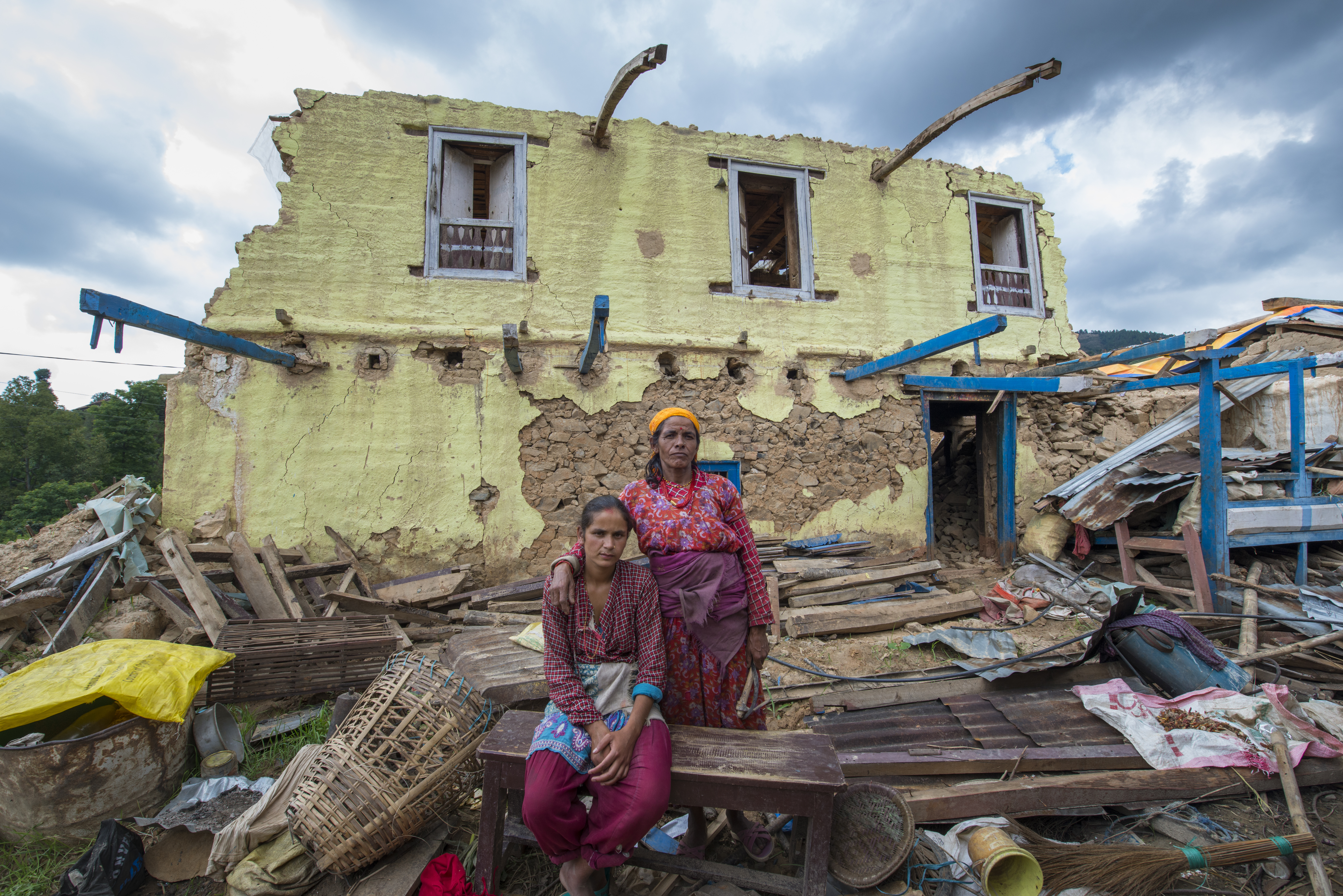 Nepal, Kavre District, Nala, earthquake relief efforts. Visiting destroyed homes on TEWA project supported by Global Fund for Women. Laxmi Dahal (21) and her mother in law, Nirmala, in front of their destroyed home. TEWA is now helping to financially support them.